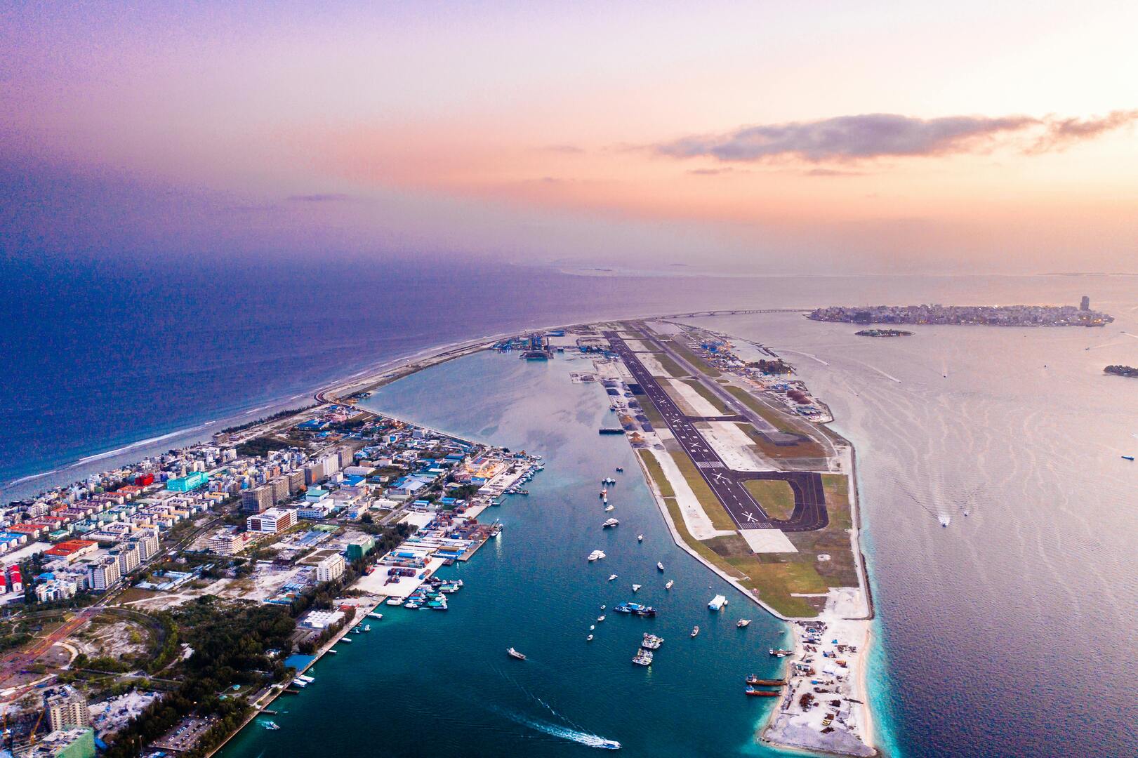 Velana International Airport (MLE) aerial view with seaplanes, speedboats, and turquoise lagoon waters